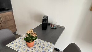A modern dining area with a table, chairs, a coffee machine, and a potted plant. - Studio Apartment 'Lucas' Neudietendorf with Wi-Fi (Nesse-Apfelstädt)