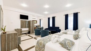 A modern hotel room with a large bed, a sofa, a desk, and a TV. - Hasthi Boutique Hotel (Kandy)