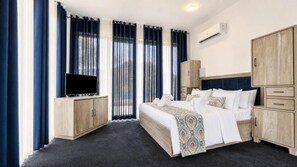 A hotel room with a bed, a TV, wooden cabinets, and a window with curtains. - Hasthi Boutique Hotel (Kandy)