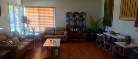 A living room with a sofa, armchair, coffee table, and a bookshelf.