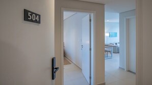 Ein Flur mit einer Tür, an der '504' steht, die zu einem Zimmer mit Bett und Schreibtisch führt.