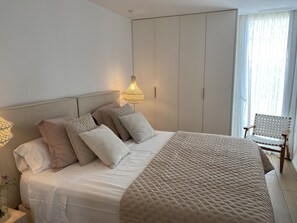Une chambre à coucher avec un lit, des oreillers, une lampe de chevet, une chaise et une armoire.