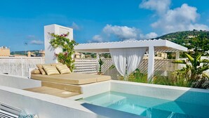 Ein Poolbereich auf dem Dach mit Sitzgelegenheit und einer Pergola.
