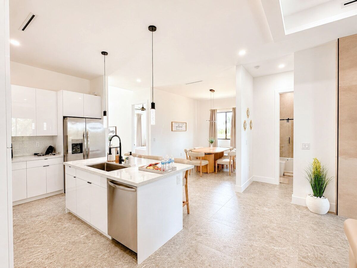 A modern kitchen with white cabinetry, a central island, and pendant lighting.