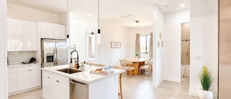 A modern kitchen with white cabinetry, a central island, and pendant lighting.