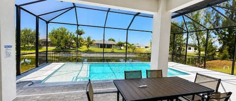 A covered outdoor area with a pool, a table, and chairs.