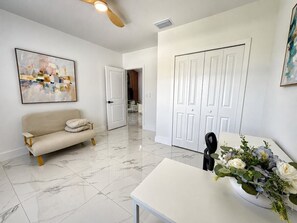 Un interior moderno con un sofá, una mesa con un jarrón de flores y una puerta que da a otra habitación.