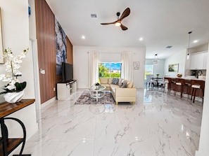A modern living room with a sofa, coffee table, and a ceiling fan. - Palm Paradise on the Canal (Cape Coral)