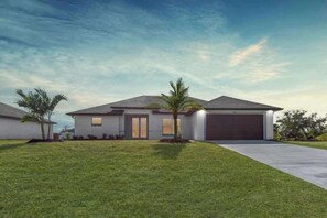 Een modern gelijkvloers huis met garage, een verzorgd gazon en een palmboom.