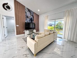 A modern living room with a sofa, a flat-screen TV, and a large window. - Palm Paradise on the Canal (Cape Coral)