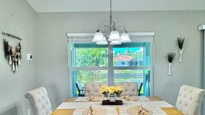 A dining room with a wooden table, cushioned chairs, a bench, and a hanging light fixture. - Cape Coral Waterfront Oasis (Cape Coral)