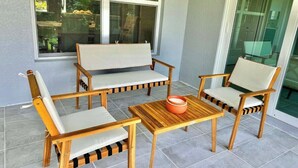 A patio with four wooden chairs and a table, a window with blinds, and a door with a glass panel. - Cape Coral Waterfront Oasis (Cape Coral)