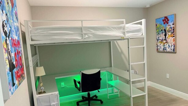 A bunk bed with a desk and chair underneath, a ladder, and a trash bin to the side. - Cape Coral Waterfront Oasis (Cape Coral)