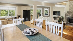 Una cocina amplia con muebles blancos, una mesa de comedor con sillas y una chimenea.
