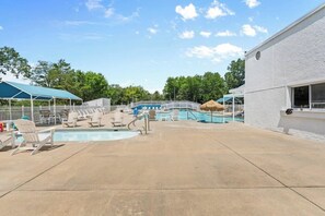 A pool area with lounge chairs, a pool, and a building with a white exterior. - Timber and Trail  2BR/2BA Family Friendly (Kimberling City)