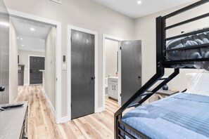 Ein Schlafzimmer mit einem Etagenbett, einem Schreibtisch mit Stuhl und einem durch eine offene Tür einsehbaren Badezimmer.