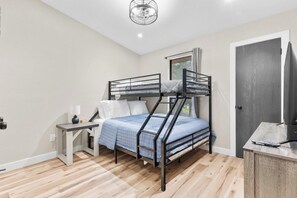 Una cama litera con escritorio y silla, un televisor y una puerta.