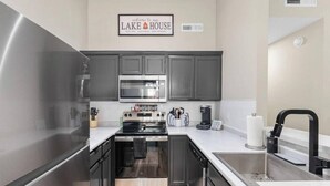 A modern kitchen with stainless steel appliances, a microwave, and a coffee maker. - Timber and Trail  2BR/2BA Family Friendly (Kimberling City)