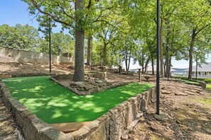 A courtyard with a green lawn, stone walls, and trees. - Timber and Trail  2BR/2BA Family Friendly (Kimberling City)