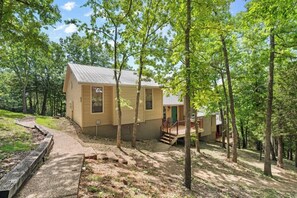 Eine Holzhütte mit einer Holzterrasse, einer kleinen Veranda und einem Feldweg, der zum Eingang führt.