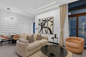 Ein modernes Wohnzimmer mit einer Couch, Sesseln, einem Esstisch und abstrakter Kunst an der Wand.