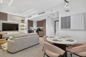 Ein stilvolles Wohnzimmer mit einer Couch, einem Esstisch für vier Personen und einer Küche im Hintergrund.