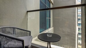 Ein Balkon mit einem Stuhl, einem kleinen Tisch und einem großen Fenster.
