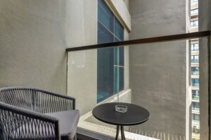 Ein Balkon mit einem Stuhl, einem kleinen Tisch und einem großen Fenster.