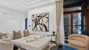 Ein modernes Hotelzimmer mit einem Bett, einem Sofa, einem runden Tisch und abstrakter Kunst an der Wand.
