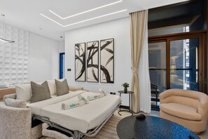 Ein modernes Hotelzimmer mit einem Bett, einem Sofa, einem runden Tisch und abstrakter Kunst an der Wand.