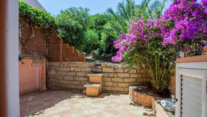 A patio with tiled flooring, a stone wall, and a wooden fence. - GuestHost - Palau Comfy Flat with Balcony (Palau)