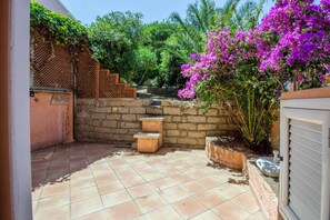 Eine Terrasse mit gefliestem Boden, einer Steinmauer und einem Holzzaun.