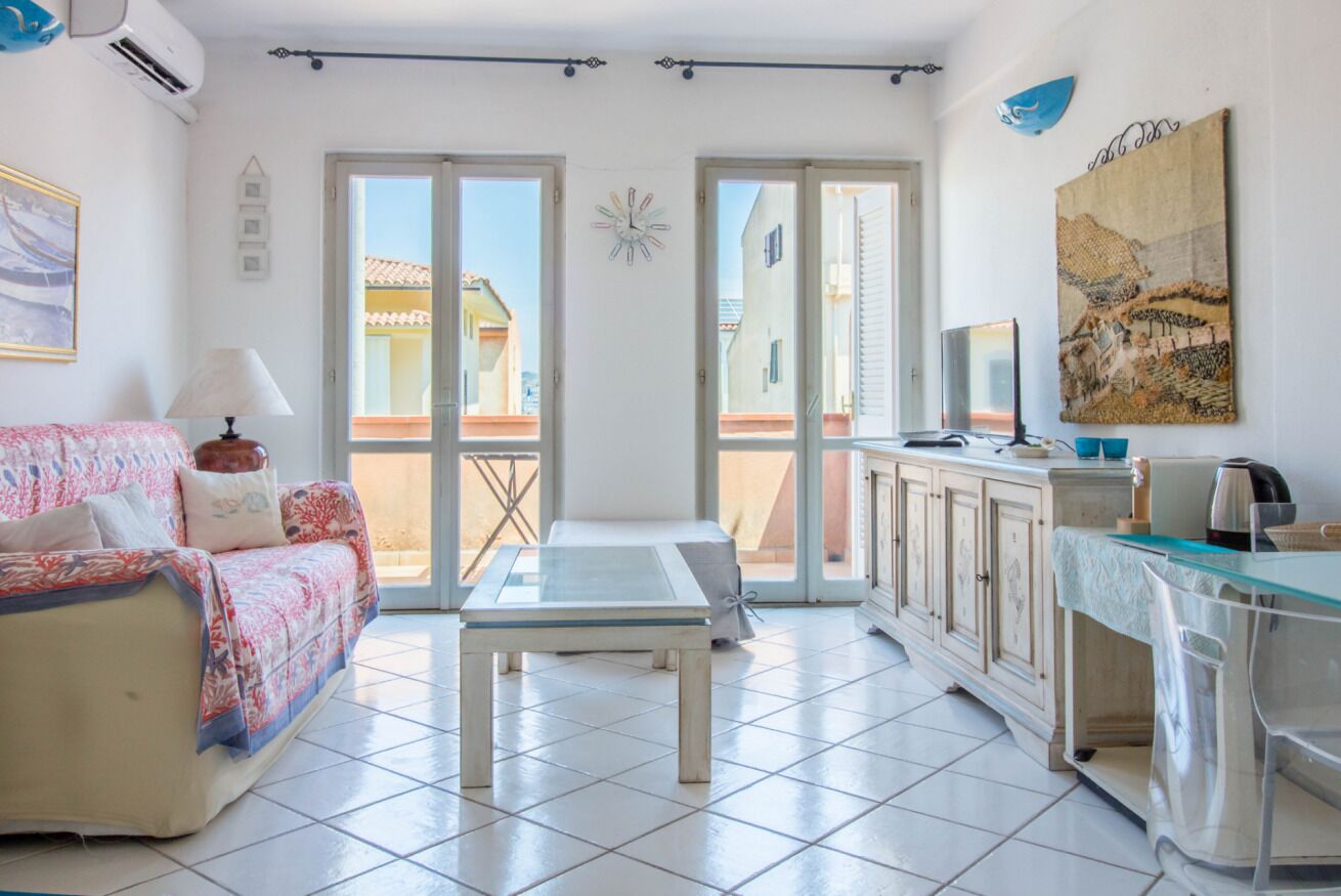 Een kamer met een bank, een tafel, een kast en uitzicht door een glazen deur.