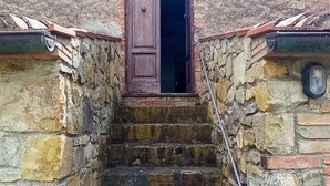 Una serie di gradini in pietra che conducono a una porta di legno con ringhiera in metallo.