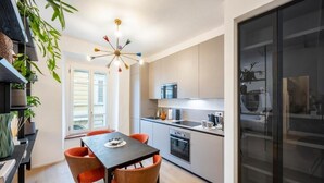 A modern kitchen with a dining table, chairs, and a refrigerator. - Palazzo Garibaldi Parma (Parma)