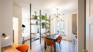 A modern dining area with a black table, orange chairs, and a plant shelf. - Palazzo Garibaldi Parma (Parma)