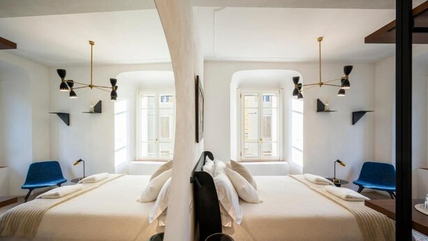 A mirrored room with two beds, a large window, and a chandelier. - Palazzo Garibaldi Parma (Parma)