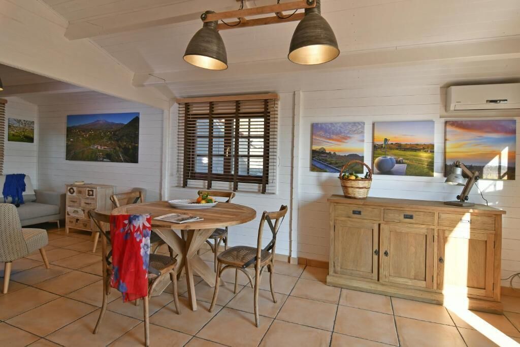 Un comedor con mesa y sillas de madera, una ventana con persianas y un mueble con una cesta encima.