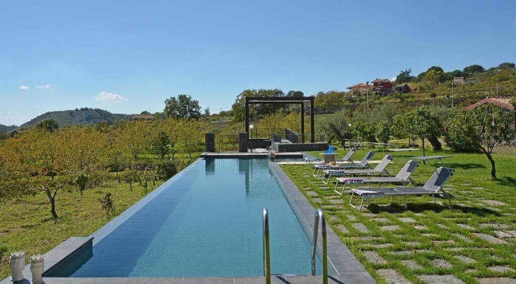 Una piscina con sillas de descanso y una pérgola.