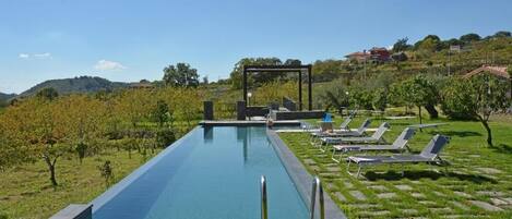 Una piscina con sillas de descanso y una pérgola.