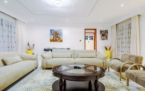 A modern living room with a sofa set, a coffee table, and artwork on the walls. - 5 BDR Lake Naivasha Retreat (Karagita)