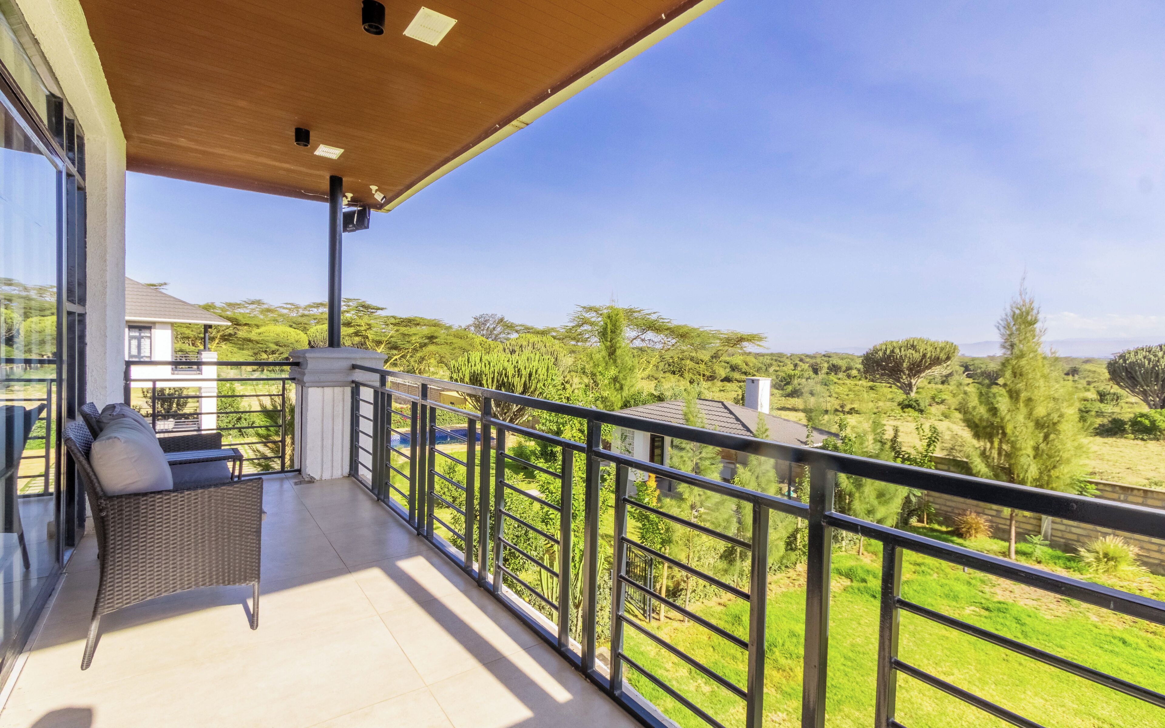 Un balcone con vista su un paesaggio verdeggiante, una sedia in vimini e una porta in vetro.