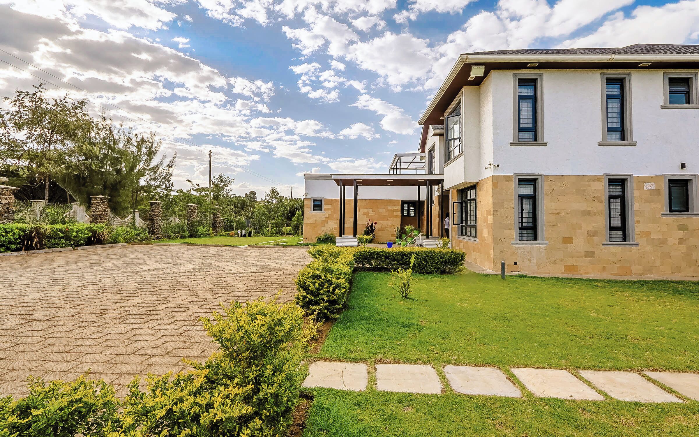 Una casa moderna a due piani con vialetto lastricato, prato curato e colonne in pietra.