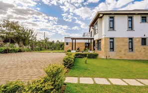 Une maison moderne à deux étages, dotée d’une allée pavée, d’une pelouse bien entretenue et de piliers en pierre.