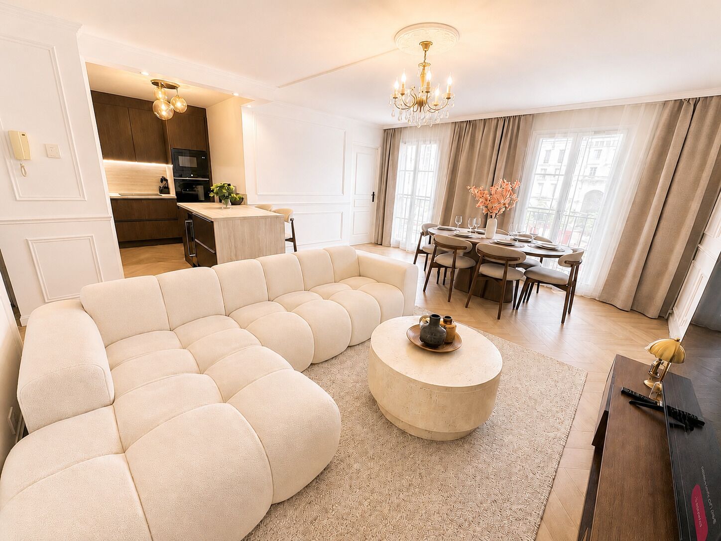 Een moderne woonkamer met een hoekbank, een ronde salontafel en een eethoek met een kroonluchter.