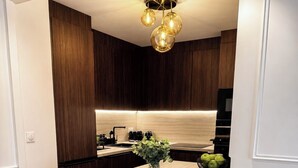 Een moderne keuken met een centraal eiland, barstoelen en een hangende lamp.