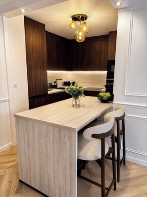 A modern kitchen with a central island, bar stools, and a pendant light fixture. - NEW - Haussmann-Style Appartment - 6 Guests - Disney & shopping (Serris)