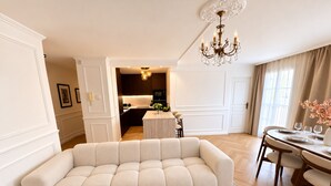 Een moderne woonkamer met een hoekbank, een eethoek met een ronde tafel, en een keuken op de achtergrond.