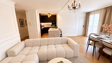 En moderne stue med en modulsofa, et spiseområde med et rundt bord, og et køkken i baggrunden.