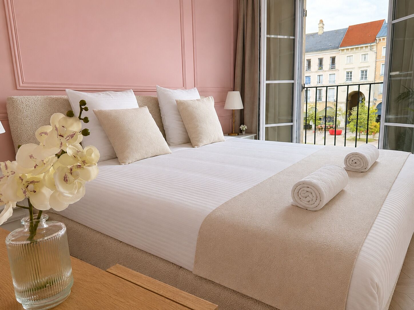 Quarto de hotel com uma cama grande, um vaso de flores e vista para edifícios.
